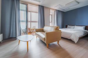 ein Schlafzimmer mit einem Bett, einem Stuhl und einem Tisch in der Unterkunft The November Stay In landmark in Incheon