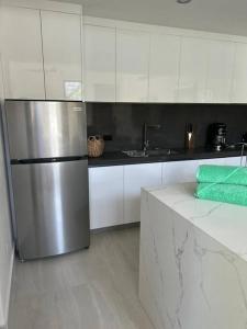 uma cozinha com um frigorífico de aço inoxidável e armários brancos em Casa Kaiman - Apartment Rincon em Nosara