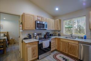 a kitchen with wooden cabinets and a sink and a microwave at Bear Paw Cabin new construction near Yosemite in Mariposa