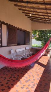 a hammock in a house with two chairs and a television at Casa de Temporada - Solar Guest House in Saquarema