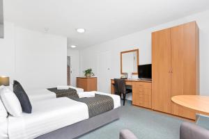 1 Schlafzimmer mit 2 Betten und einem Schreibtisch mit einem TV in der Unterkunft Peninsula Nelson Bay Motel and Serviced Apartments in Nelson Bay