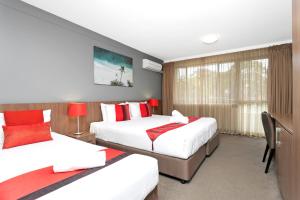 a hotel room with two beds and a window at Peninsula Nelson Bay Motel and Serviced Apartments in Nelson Bay