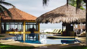 un complejo con una piscina con sillas y una cabaña en Hotel Bella vista en Zihuatanejo