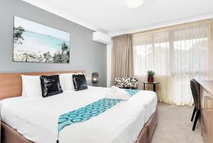 sypialnia z dużym białym łóżkiem i oknem w obiekcie Peninsula Nelson Bay Motel and Serviced Apartments w mieście Nelson Bay
