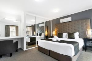 een slaapkamer met een groot bed en een grote spiegel bij Peninsula Nelson Bay Motel and Serviced Apartments in Nelson Bay