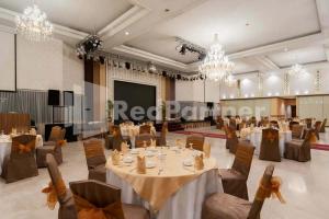 un salón de banquetes con mesas, sillas y lámparas de araña en Selecta Hotel Medan Petisah R Signature Mitra RedDoorz, en Medan