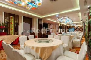 a banquet hall with white chairs and tables and a chandelier at Selecta Hotel Medan Petisah R Signature Mitra RedDoorz in Medan