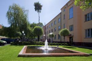 une fontaine dans l'herbe devant un bâtiment dans l'établissement Hotel Plock, à Płock