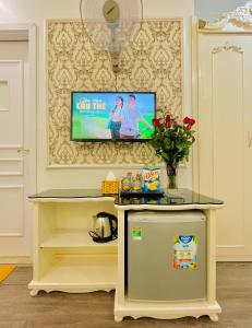 河内Diamond Hotel Ha Noi的墙上的电视、桌子和冰箱