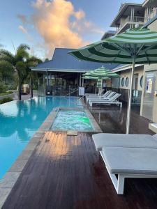 a swimming pool with two umbrellas and chairs and a swimming pool at Sea La Vie in Airlie Beach