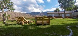 dos sillas de madera sentadas en el césped en un patio en Esencia Cabaña en Potrerillos