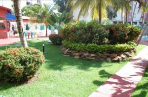 a garden with bushes and flowers and palm trees at Hot springs - suíte Premium in Caldas Novas