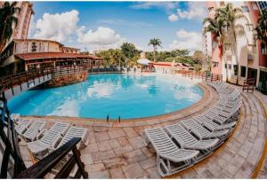 a large swimming pool with white chairs in a resort at Hot springs - suíte Premium in Caldas Novas