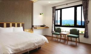 a bedroom with a bed and two chairs and a window at Do Tian Ding B&B in Lugu