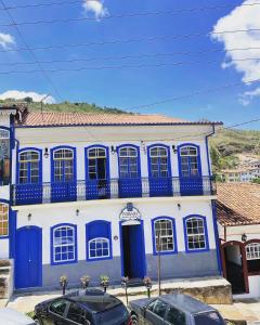 niebiesko-biały budynek z samochodami zaparkowanymi przed nim w obiekcie Caminhos da Liberdade Pousada w mieście Ouro Preto