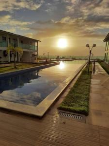 a swimming pool with the sunset in the background at Excelente Bangalô/duplex em Jacumã - PB in Conde