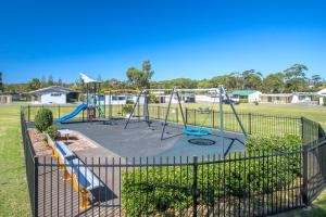 a playground with a swing set in a park at Lakeside Cabins & Holiday Village in Sussex inlet