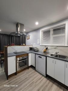 una cocina con armarios blancos y electrodomésticos de acero inoxidable en Stylish Homestay Close CBD en Hamilton