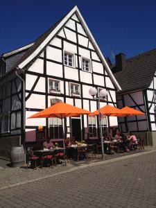 un edificio en blanco y negro con mesas y sombrillas naranjas en Zweite Heimat Ferienwohnungen en Herdecke