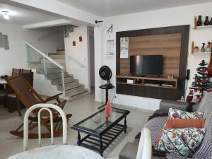 a living room with a couch and a tv at Excelente Bangalô/duplex em Jacumã - PB in Conde