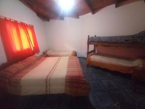 1 Schlafzimmer mit 2 Betten und einem roten Fenster in der Unterkunft Hospedaje Ale in Iruya