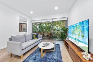 a living room with a couch and a large screen tv at Centre of Newtown 2 Bed Apartment in Sydney
