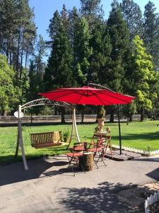 un ombrellone e sedie rossi in un parco di Spacious upstairs studio with kitchenette & 1 bath a Grants Pass