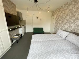 a bedroom with a white bed and a green chair at Cosy Bright Studio Apartment Close to Wembley Stadium in London