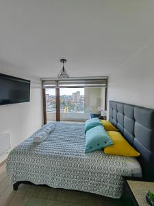 um quarto com uma cama grande com almofadas azuis e amarelas em Departamento céntrico en Temuco con estacionamiento em Temuco