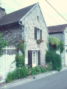 a brick house with a white fence and flowers at Le Havre de Bennecourt in Bennecourt