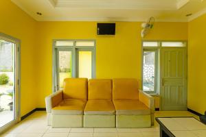 - un salon jaune avec un canapé et une télévision dans l'établissement OYO 92483 Hotel Kirana, à Port Elgin