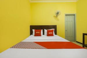 - une chambre avec un lit et deux oreillers orange dans l'établissement OYO 92483 Hotel Kirana, à Port Elgin