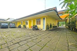 a yellow house with motorcycles parked in a parking lot at OYO 92486 Hotel Permata 3 in Salatiga