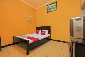 a bedroom with a bed with red pillows and a tv at OYO 92486 Hotel Permata 3 in Salatiga