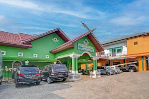 ein grünes Gebäude mit Autos auf einem Parkplatz in der Unterkunft OYO 92501 Wisma Sakinah Syariah in Rambah