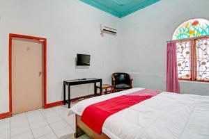 Schlafzimmer mit einem Bett, einem Schreibtisch und einem Fenster in der Unterkunft OYO 92501 Wisma Sakinah Syariah in Rambah