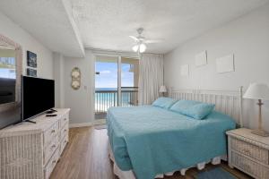 ein Schlafzimmer mit einem blauen Bett und einem TV in der Unterkunft Pelican Beach 1816 by Pelican Beach Management in Destin