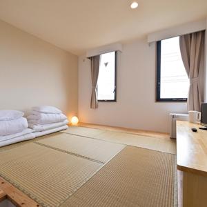 a bedroom with a bed and two windows at Pangoo Onna Japanese Style Hotel in Onna