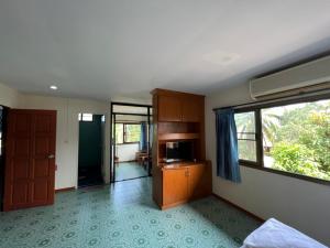 a room with a bed and a tv and a window at Baan Wang Bua in Ban Khok Kroat