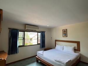 a bedroom with a large bed and a window at Baan Wang Bua in Ban Khok Kroat