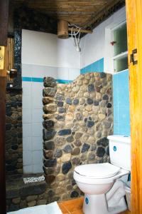 baño con aseo y pared de piedra en Termales SironaSpa, en Gama