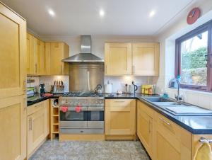 a kitchen with wooden cabinets and a stove top oven at Old Lock Cottage, Birdham in Birdham