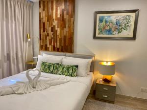 a bedroom with a white bed with a lamp and a painting at New Cosy Apartment at Marvest Huahin City Center in Hua Hin