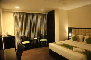 um quarto de hotel com uma cama, uma mesa e cadeiras em J Hotel em Port Blair