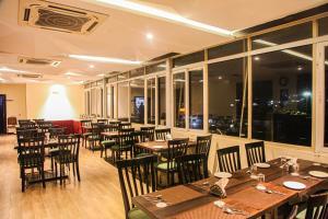 um restaurante com mesas e cadeiras de madeira e janelas em J Hotel em Port Blair