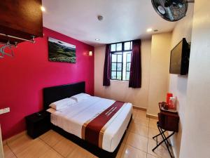 ein Schlafzimmer mit einem Bett und einer roten Wand in der Unterkunft Hotel Sun Birds in Cameron Highlands