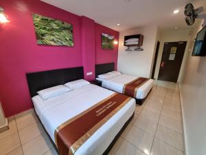 2 Betten in einem Zimmer mit einer rosa Wand in der Unterkunft Hotel Sun Birds in Cameron Highlands