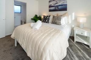 a bedroom with a large white bed with pillows at Indulge in Christchurch Hagley Park 2 bed 2 bath in Christchurch