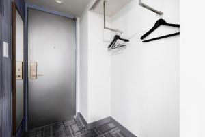 einen Flur mit einer Tür und Kleiderbügeln an der Wand in der Unterkunft Hotel Wing International Shizuoka in Shizuoka