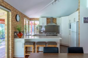 a kitchen with white cabinets and a table and chairs at Mansfield Retreat - In Town - Margaret River in Margaret River Town